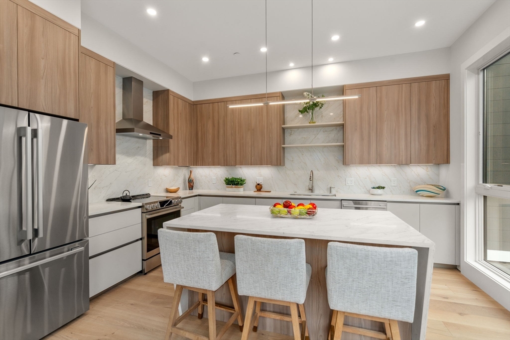 2202 Commonwealth Avenue, Unit 1 Newton, MA 02466 - Photo 12 of 34 a kitchen with stainless steel appliances granite countertop a refrigerator a stove a sink a dining table and chairs
