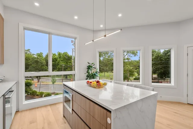a view of a kitchen with kitchen island a large window wooden floor and a sink