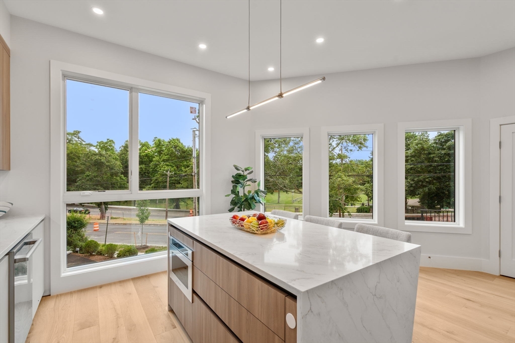2202 Commonwealth Avenue, Unit 1 Newton, MA 02466 - Photo 14 of 34 a view of a kitchen with kitchen island a large window wooden floor and a sink