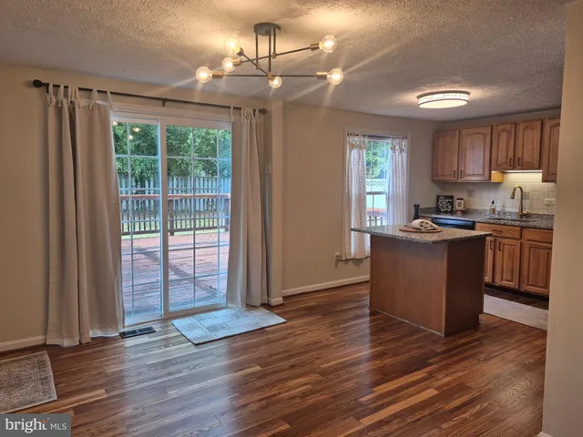 a kitchen with stainless steel appliances granite countertop white cabinets a refrigerator a sink a stove a microwave and wooden floors