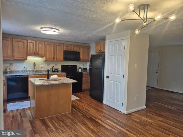 a kitchen with stainless steel appliances granite countertop a refrigerator a sink dishwasher a stove and a oven with wooden floor