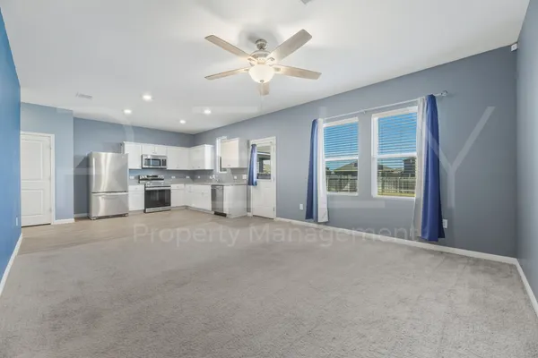 a view of an empty room with window and a kitchen