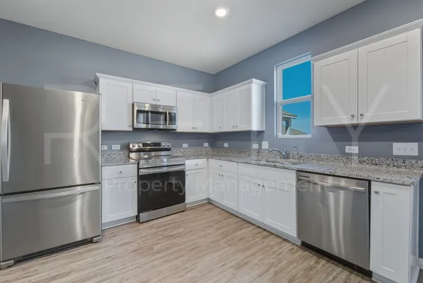 a kitchen with granite countertop white cabinets and stainless steel appliances