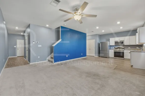 a view of an empty room with kitchen view