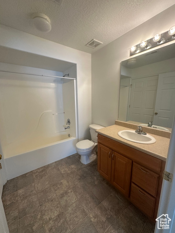 8196 North Cedar Springs Road, Unit 2 Eagle Mountain, UT 84005 - Photo 17 of 22 Full bathroom featuring bathtub / shower combination, a textured ceiling, vanity, and dark stone finish flooring
