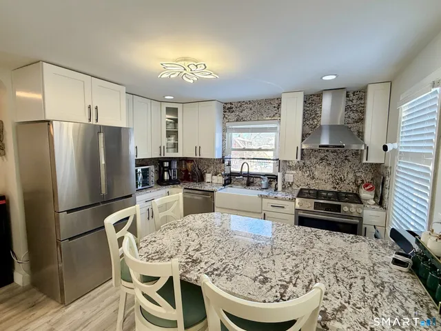 a kitchen with a refrigerator a stove a sink dishwasher with a dining table and chairs