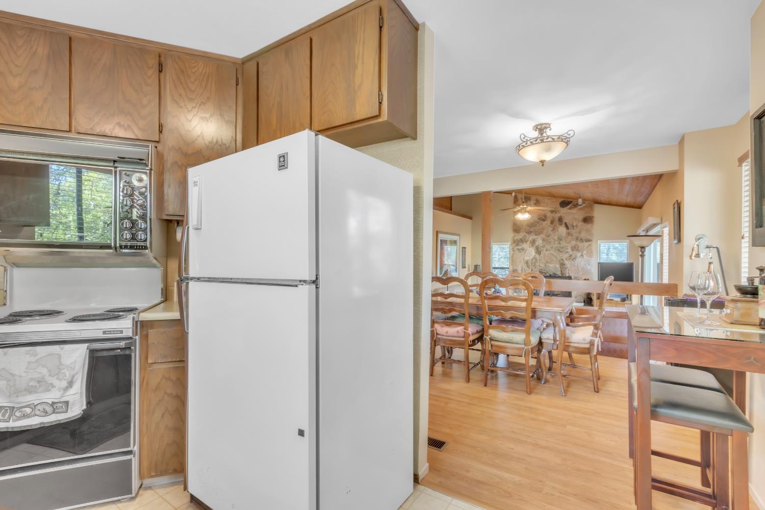 65 Poker Flat Road Copperopolis, CA 95228 - Photo 12 of 30 a kitchen with a refrigerator a stove and a dining table with wooden floor