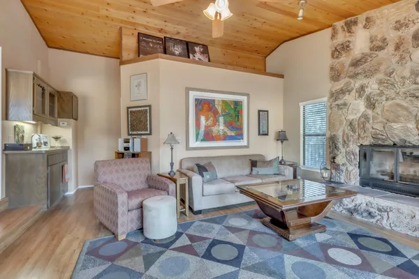 a living room with furniture a fireplace and a dining table with wooden floor