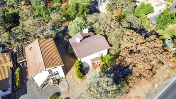 an aerial view of a house with a yard and large tree