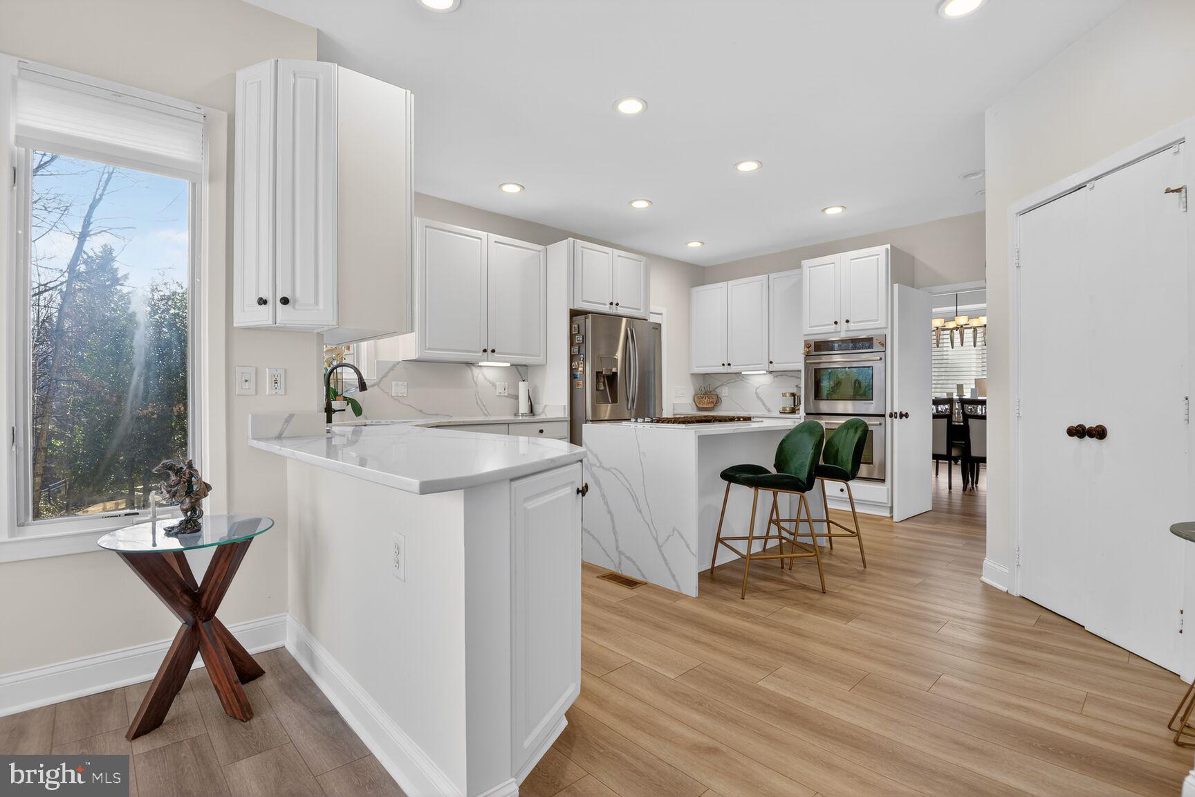 11300 Water Pointe Circle Reston, VA 20194 - Photo 14 of 36 a kitchen with stainless steel appliances kitchen island granite countertop a refrigerator a stove a sink a dining table and chairs with wooden floor