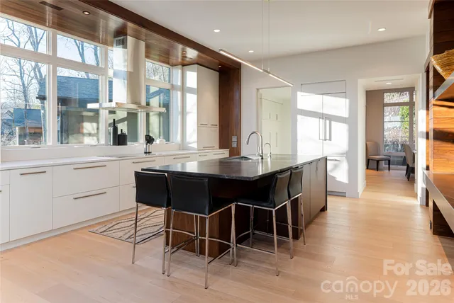 a dining hall with stainless steel appliances kitchen island granite countertop a table chairs and a large window