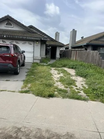 a front view of a house with a garden and parking