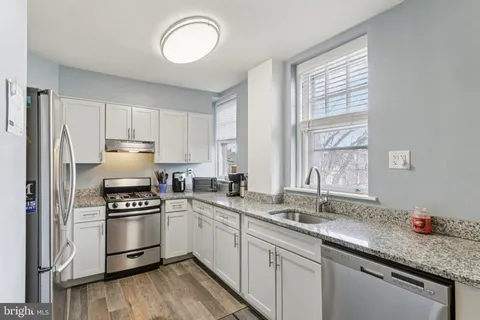 a kitchen with granite countertop a sink stainless steel appliances and white cabinets