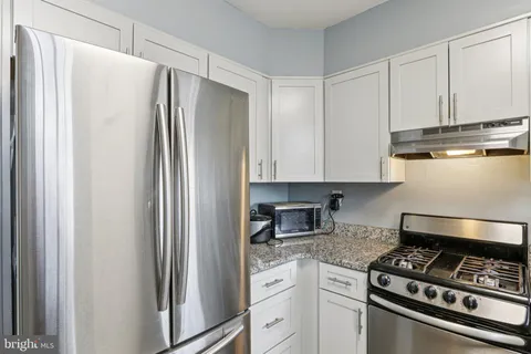 a kitchen with stainless steel appliances granite countertop a refrigerator a sink and white cabinets