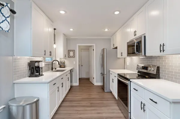 a kitchen with stainless steel appliances a sink dishwasher a stove a refrigerator and a oven with wooden floor