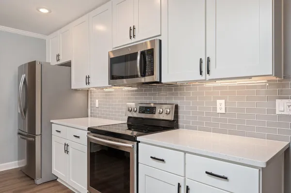 a kitchen with stainless steel appliances white cabinets and a refrigerator