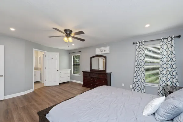 a bedroom with a bed and a dresser with wooden floor