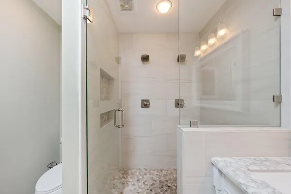 a bathroom with a granite countertop sink a toilet and shower