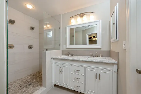a bathroom with a granite countertop sink a mirror and a shower