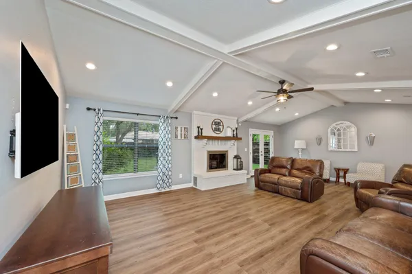 a living room with furniture large window and wooden floor
