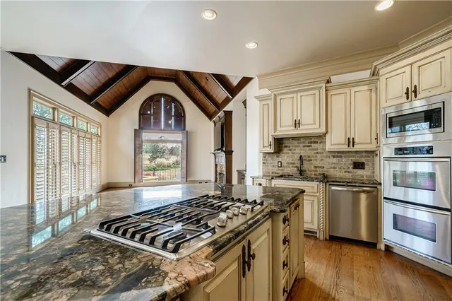 a bathroom with a granite countertop sink a large mirror and a bathtub next to a window