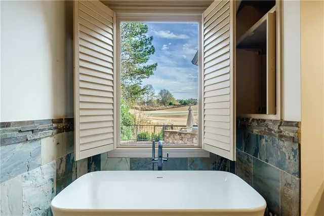 a view of a livingroom with a fireplace a ceiling fan and window