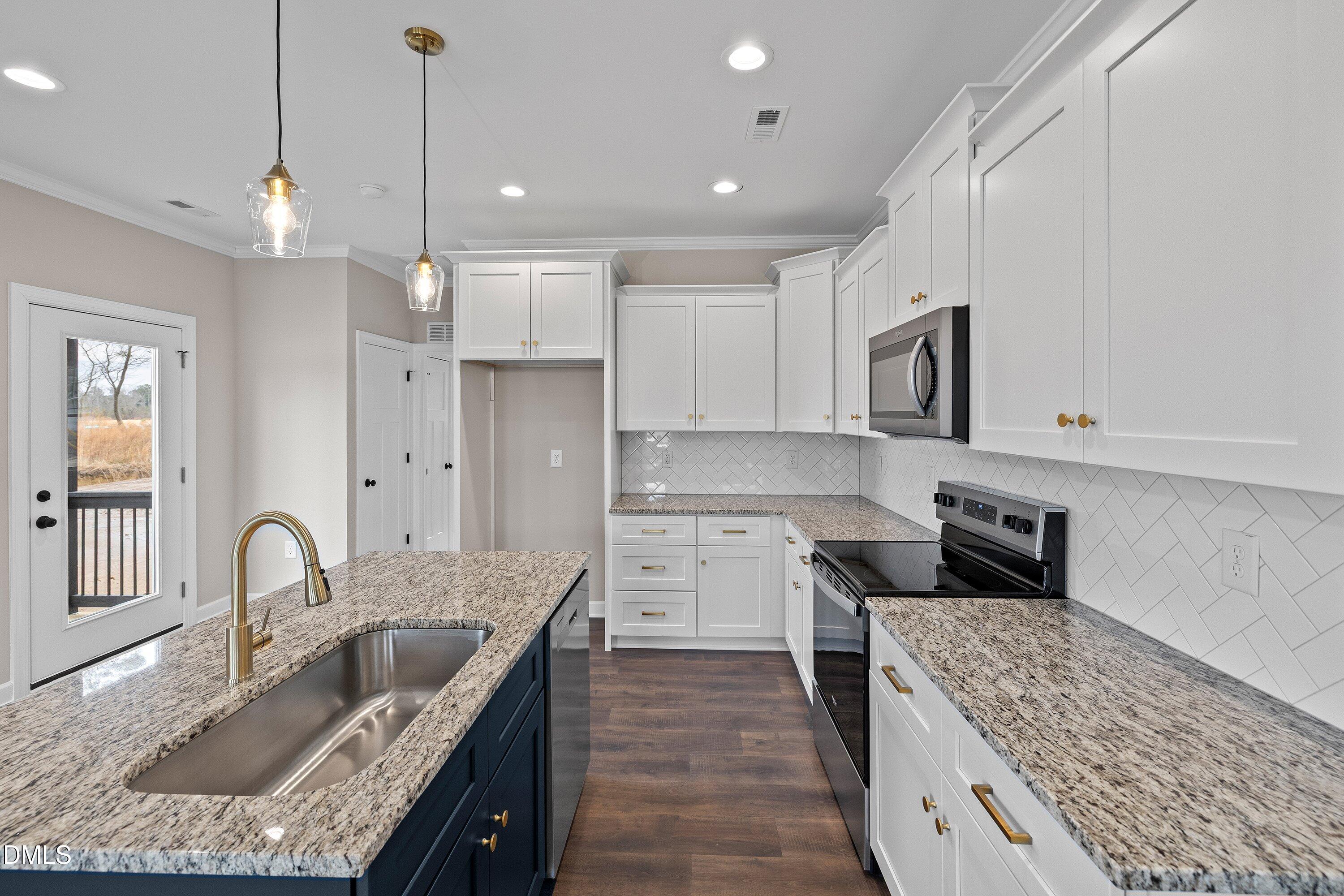 920 Micro Road West Selma, NC 27576 - Photo 16 of 32 a kitchen with kitchen island granite countertop a sink a counter space appliances and cabinets