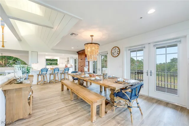 a dining room with wooden floor a chandelier a wooden table and chairs