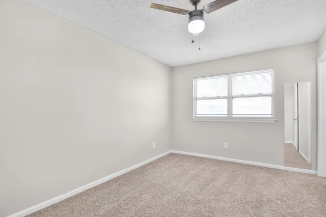 an empty room with a window and a fan