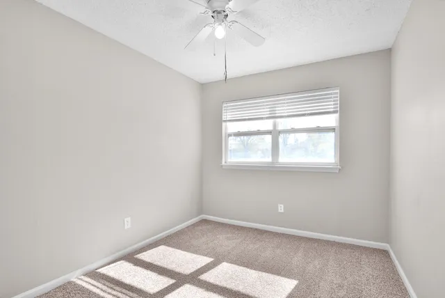 an empty room with a window and a fan
