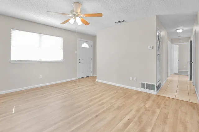 an empty room with fan and a chandelier fan