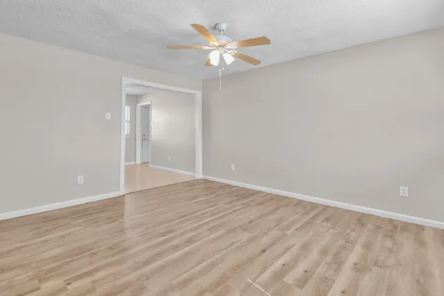 a view of an empty room with cabinet and a ceiling fan