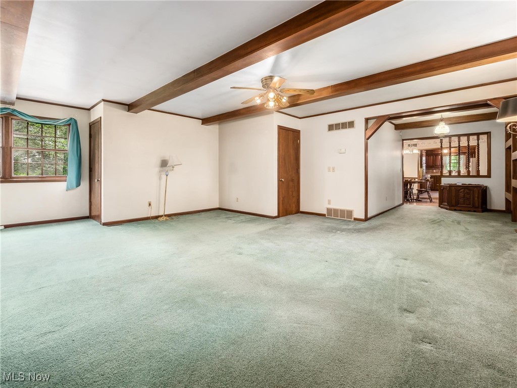 975 Richey Road Zanesville, OH 43701 - Photo 13 of 27 Unfurnished living room with a ceiling fan, beam ceiling, carpet, and baseboards
