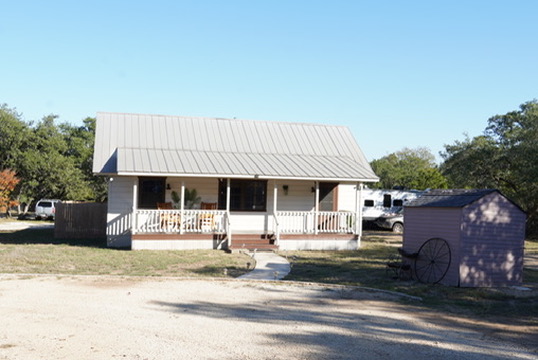 View of front of home with covered porch and a storage shed