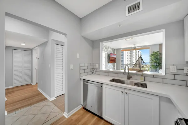 a kitchen with white cabinets appliances and a window