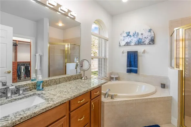 a bathroom with a granite countertop tub sink and mirror