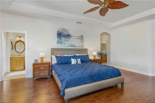 a bedroom with a bed and dresser with wooden floor