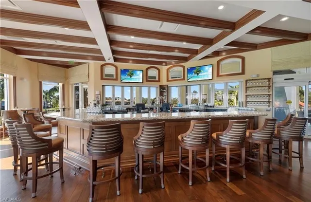 a dining hall with stainless steel appliances granite countertop a dining table chairs and wooden floor