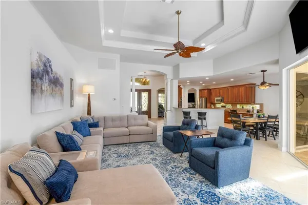 a living room with furniture kitchen view and a chandelier