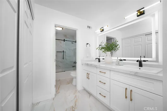 a bathroom with a granite countertop sink two mirror and a shower