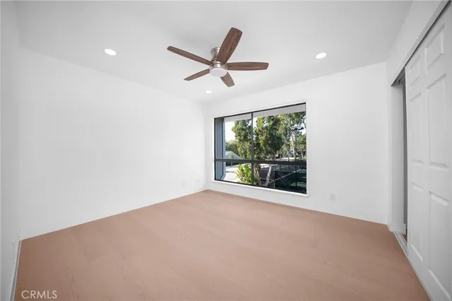 an empty room with ceiling fan and window