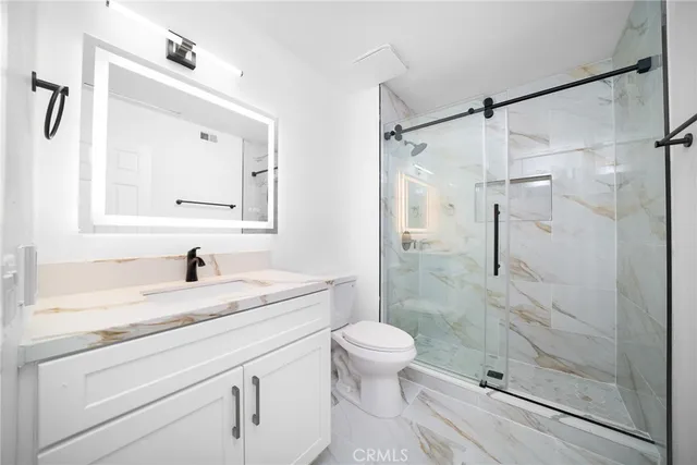 a bathroom with a granite countertop sink toilet and shower
