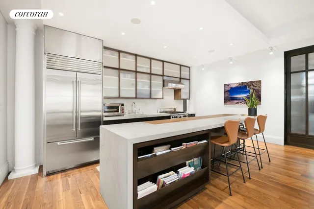 a kitchen with stainless steel appliances granite countertop a refrigerator a stove and a dining table with wooden floor