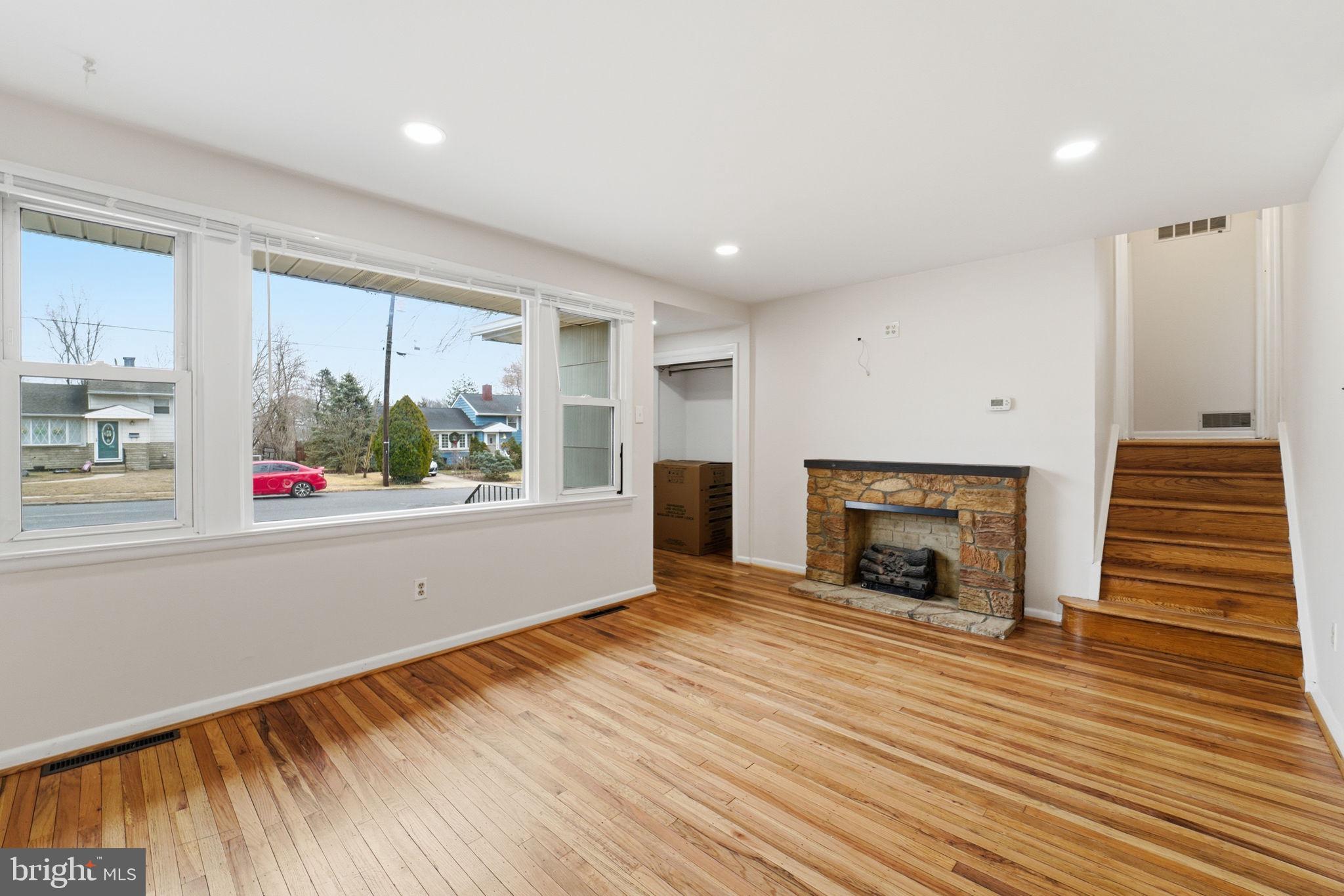 490 Hamilton Road Wenonah, NJ 08090 - Photo 14 of 49 an empty room with wooden floor a fireplace and windows
