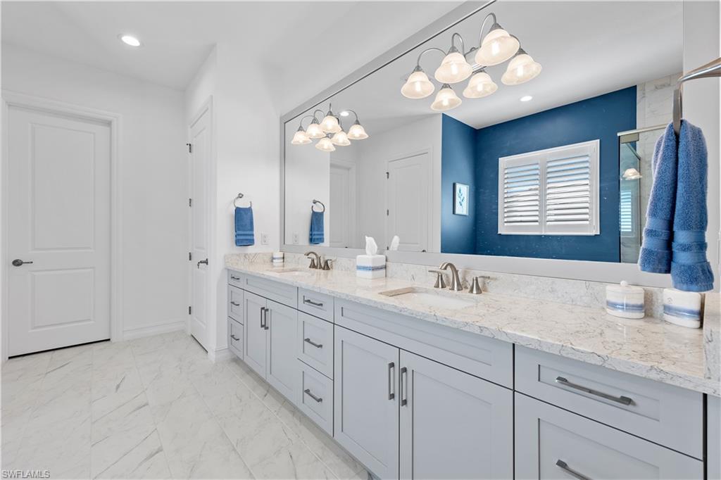14265 Laguna Springs Lane Naples, FL 34114 - Photo 15 of 40 a bathroom with double vanity sink a vanity and a large mirror
