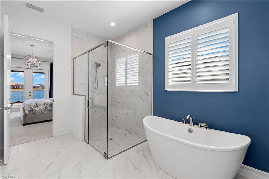 14265 Laguna Springs Lane Naples, FL 34114 - Photo 16 of 40 a bathroom with a white tub shower and bedroom