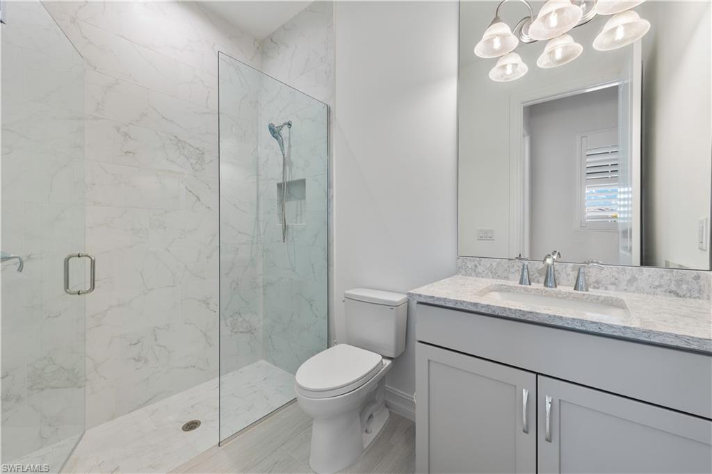 14265 Laguna Springs Lane Naples, FL 34114 - Photo 18 of 40 a bathroom with a granite countertop sink a toilet and shower