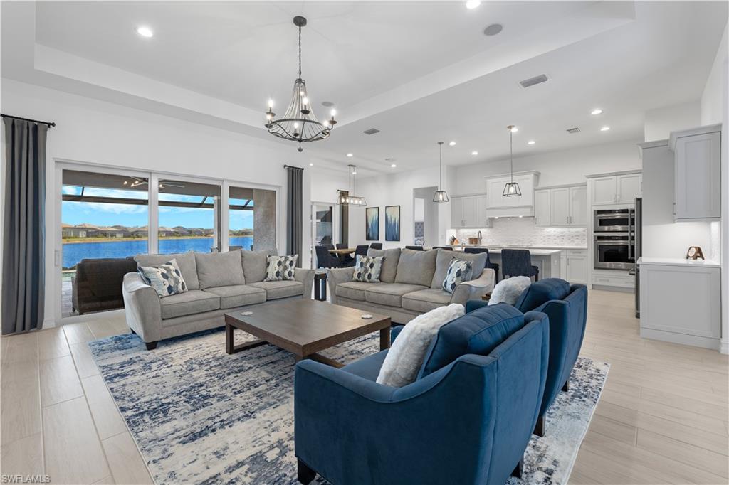 14265 Laguna Springs Lane Naples, FL 34114 - Photo 3 of 40 a living room with furniture kitchen view and a chandelier