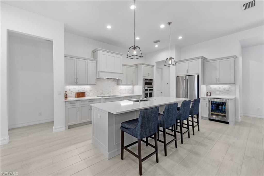 14265 Laguna Springs Lane Naples, FL 34114 - Photo 4 of 40 a kitchen with stainless steel appliances kitchen island granite countertop a table chairs sink and cabinets