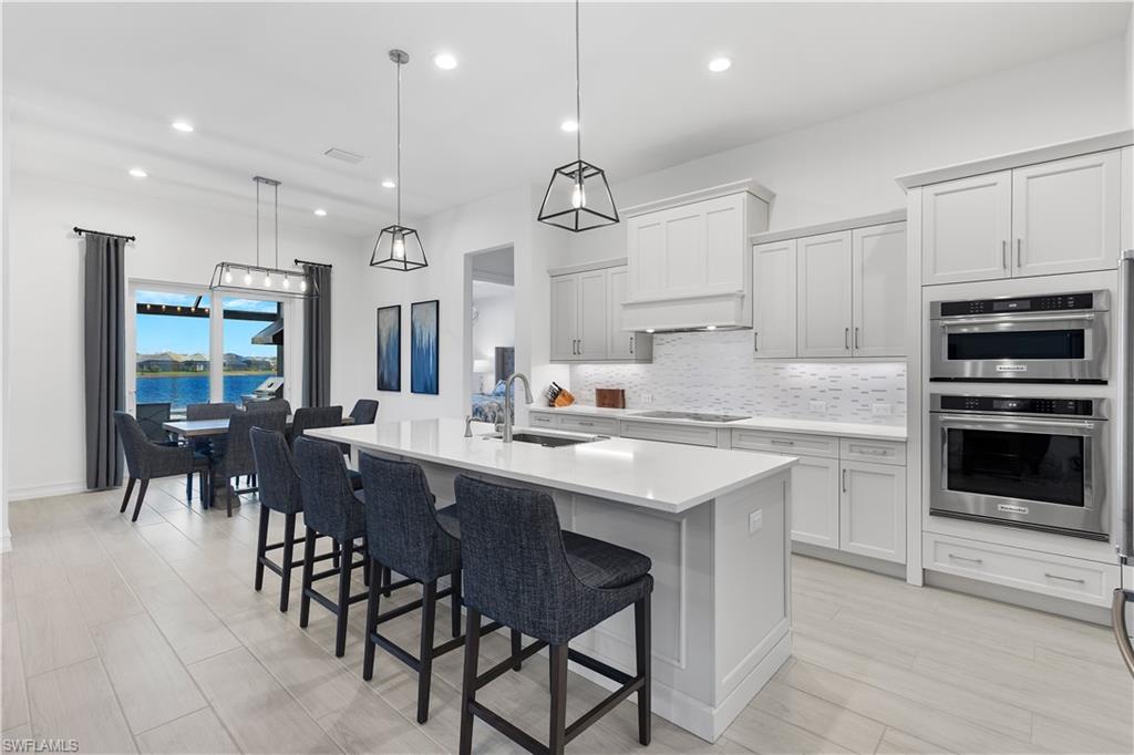 14265 Laguna Springs Lane Naples, FL 34114 - Photo 5 of 40 a kitchen with stainless steel appliances granite countertop a stove a sink a oven a dining table and chairs